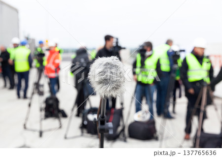 Microphone in focus against blurred camera operators and journalists at news conference 137765636
