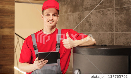 Professional Plumber Or HVAC Technician Showing Thumbs Up After Successful Heating System Inspection While Holding Digital Tablet In Boiler Room Professional Plumber Or HVAC Technician Showing Thumbs Up After Successful Heating System Inspection While Holding Digital Tablet In Boiler Room 137765791