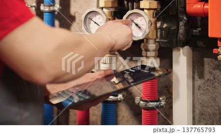 Technician Checking Heating System Gauges And Monitoring Boiler Data Using Digital Tablet In Utility Room. Residential HVAC Inspection And Plumbing Maintenance Diagnostics Concept. Technician Checking Heating System Gauges And Monitoring Boiler Data Using Digital Tablet In Utility Room. Residential HVAC Inspection And Plumbing Maintenance Diagnostics Concept. 137765793
