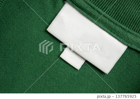 Blank white laundry care clothes label on green shirt fabric texture background 137765925