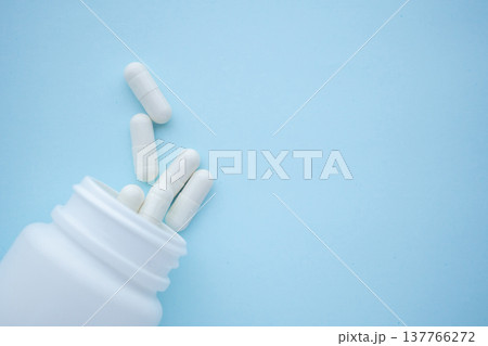 medicine pills capsule spilling out of bottle on blue background medicine pills capsule spilling out of bottle on blue background 137766272