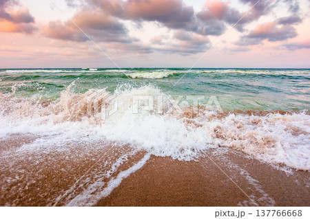 stormy weather on the sandy beach. dramatic sky over the black sea. moody summer landscape in morning light. green waves crashing the shore. majestic cloudscape above the horizon 137766668