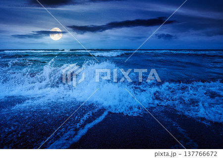stormy weather on the sandy beach at night. dramatic sky over the sea in full moon light. moody summer landscape. waves crashing the shore. mysterious cloudscape above the horizon stormy weather on the sandy beach at night. dramatic sky over the sea in full moon light. moody summer landscape. waves crashing the shore. mysterious cloudscape above the horizon 137766672