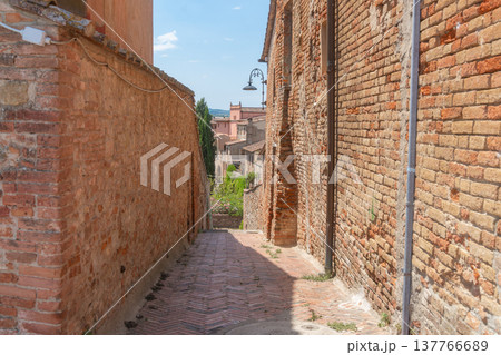 Empty narrow street in a historic European town with outdoor cafe tables. Stone walls, warm tones and calm morning atmosphere. Travel, architecture and slow life concept, Certaldo, Italy Empty narrow street in a historic European town with outdoor cafe tables. Stone walls, warm tones and calm morning atmosphere. Travel, architecture and slow life concept, Certaldo, Italy 137766689