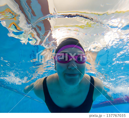 Underwater swimmer in pool wearing pink goggles 137767035
