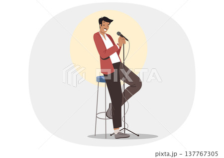 Stand-up show from man comedian standing on stage with microphone in hand, near chair and spotlight 137767305