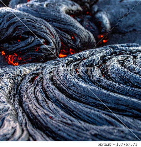Explore the intense beauty of volcanic activity with this macro of cooling lava. Its ropey texture and glowing red core evoke primeval energy, perfect for nature and science themes. 137767373
