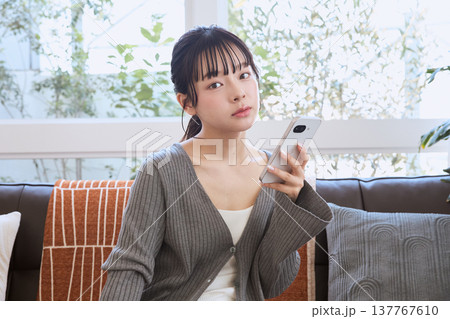 スマートフォンを持って考える女性 リビングでくつろぐライフスタイル スマートフォンを持って考える女性 リビングでくつろぐライフスタイル 137767610