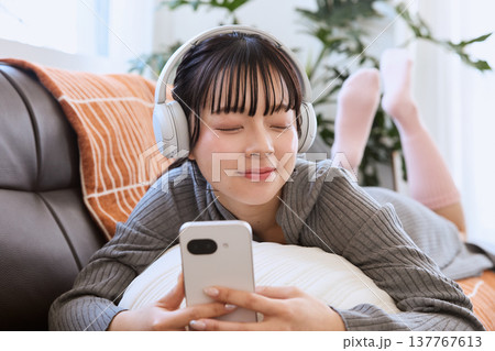 ヘッドホンで音楽を楽しむ女性 スマートフォンと過ごすリラックスタイム ヘッドホンで音楽を楽しむ女性 スマートフォンと過ごすリラックスタイム 137767613