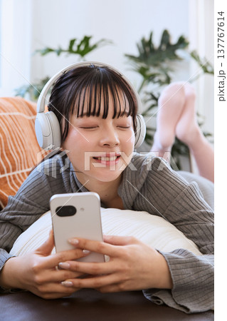 ヘッドホンで音楽を楽しむ女性　スマートフォンと過ごすリラックスタイム 137767614