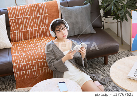 ヘッドホンをつけて本を読みながら考える若い女性 ヘッドホンをつけて本を読みながら考える若い女性 137767623
