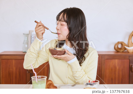 アサイーボウルを食べる若い女性の健康的な朝食シーン 137767638