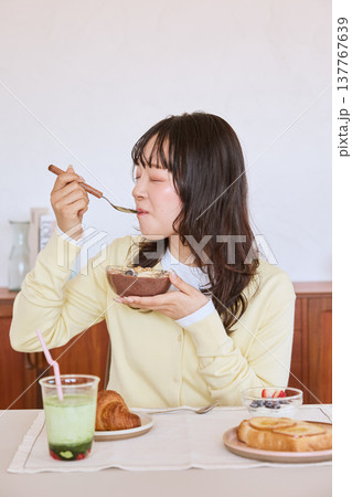アサイーボウルを食べる若い女性の健康的な朝食シーン 137767639