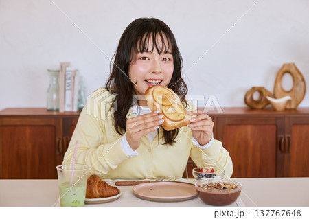 自宅で朝食のトーストを食べる若い女性 137767648