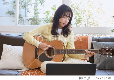 オンラインでギターを練習する女性 137767656