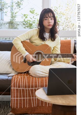 自宅でギターを練習する女性のライフスタイル 137767657