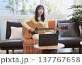 オンラインでギターを練習する若い女性 137767658