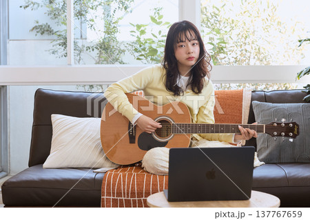 オンラインでギターを学ぶ若い女性 137767659