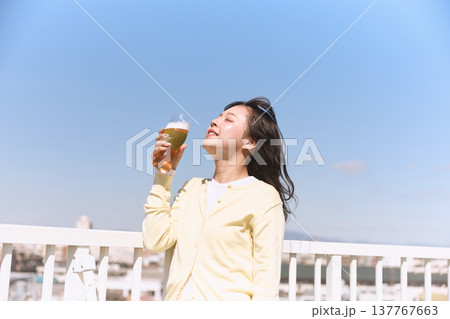青空の下でビールを楽しむ若い女性 青空の下でビールを楽しむ若い女性 137767663