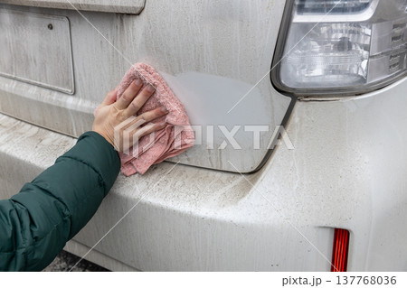 汚れた車のボディーを雑巾で水拭きしている 137768036