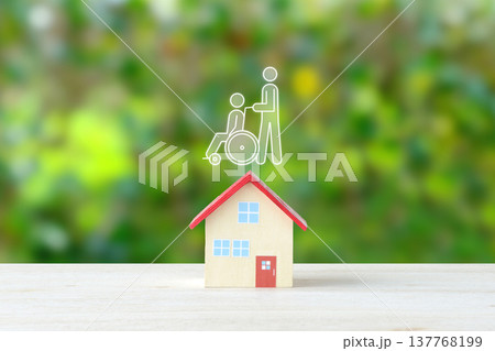 自宅介護やバリアフリー化のイメージ―住宅のオブジェクトと車椅子に乗った人物のピクトグラム 137768199