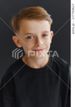 Young boy smiles against a dark background during a photo session Young boy smiles against a dark background during a photo session 137768627