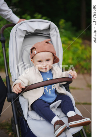 Cute toddler in stroller enjoying a sunny day outdoors 137768690