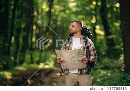 Map in hands. Male tourist is with backpack in the forest 137768816