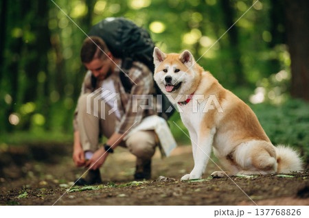 Ties shoelaces. Man tourist is with his dog in the forest Ties shoelaces. Man tourist is with his dog in the forest 137768826