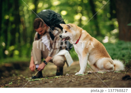 Ties shoelaces. Man tourist is with his dog in the forest Ties shoelaces. Man tourist is with his dog in the forest 137768827