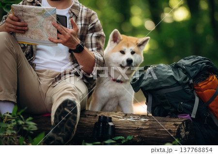 On a log, sitting. Man tourist is with his dog in the forest 137768854