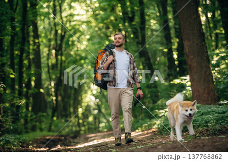 New places, exploring, walking, front view. Man tourist is with his dog in the forest 137768862