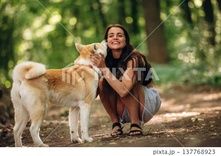 Happy woman is with Shiba Inu dog in the forest Happy woman is with Shiba Inu dog in the forest 137768923
