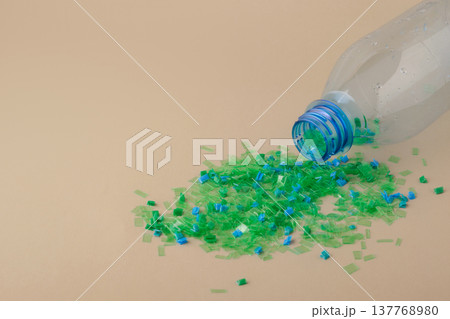 Empty plastic bottles spilling colorful crushed microplastic flakes illustrate the process of recycling and material recovery. Circular economy, green technologies Empty plastic bottles spilling colorful crushed microplastic flakes illustrate the process of recycling and material recovery. Circular economy, green technologies 137768980