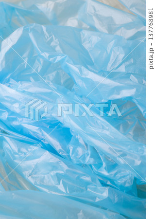 Crumpled blue plastic creating an abstract background texture. Showing wrinkles, folds, and highlights on transparent polyethylene material Crumpled blue plastic creating an abstract background texture. Showing wrinkles, folds, and highlights on transparent polyethylene material 137768981