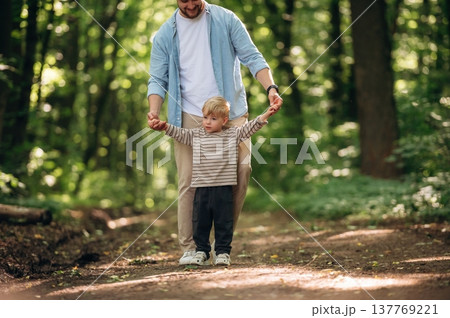 Holding hands, walking. Dad with his little boy son is in the forest 137769221