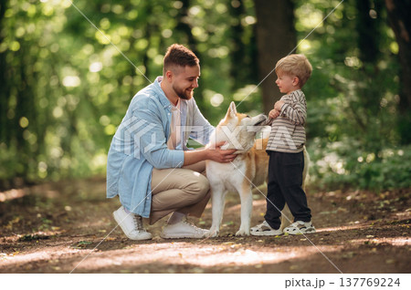 Sitting, playing with pet. Father with son and dog are in the forest 137769224