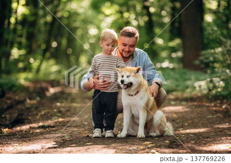 Sitting, playing with pet. Father with son and dog are in the forest 137769226