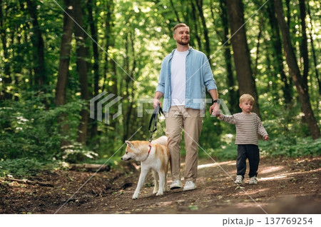 Exploration conception, walking together. Father with son and dog are in the forest Exploration conception, walking together. Father with son and dog are in the forest 137769254