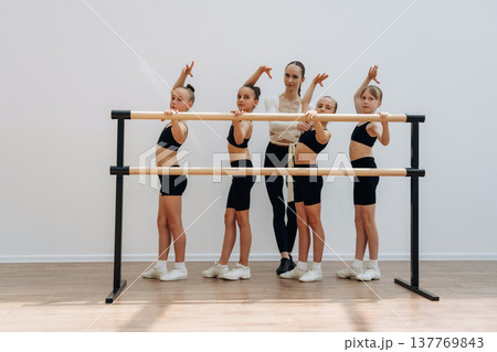 Hands up, flexibility. Trainer is teaching girls ballet dancing Hands up, flexibility. Trainer is teaching girls ballet dancing 137769843