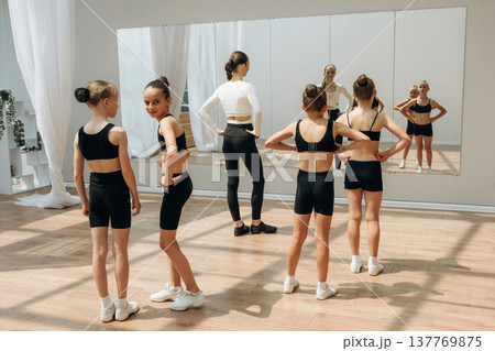 Looking at the mirror. Trainer is teaching girls ballet dancing Looking at the mirror. Trainer is teaching girls ballet dancing 137769875