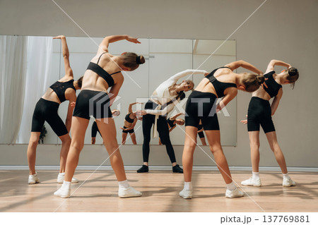Rear view. Trainer is teaching girls ballet dancing Rear view. Trainer is teaching girls ballet dancing 137769881