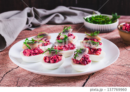 Egg halves stuffed with herring under a fur coat on a plate on the table Egg halves stuffed with herring under a fur coat on a plate on the table 137769960