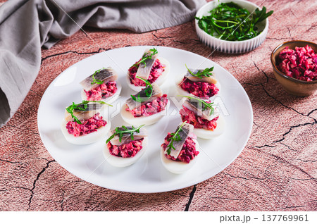 Eggs delived with vegetable salad, a piece of herring and arugula on a plate on the table Eggs delived with vegetable salad, a piece of herring and arugula on a plate on the table 137769961