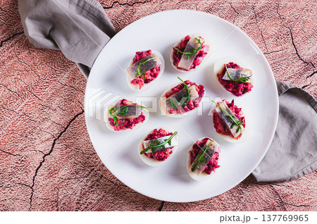 Close up of egg halves stuffed with herring under a fur coat on a plate on the table top view Close up of egg halves stuffed with herring under a fur coat on a plate on the table top view 137769965