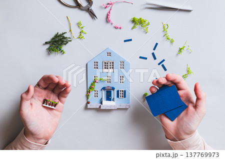 Details for assembling a model of a house in children's palms on a blue background, top view Details for assembling a model of a house in children's palms on a blue background, top view 137769973
