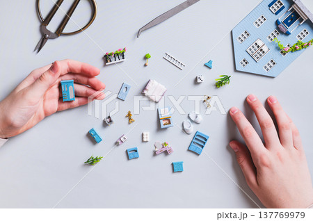 Miniature details and furniture for a toy house and children's hands on a blue top view 137769979
