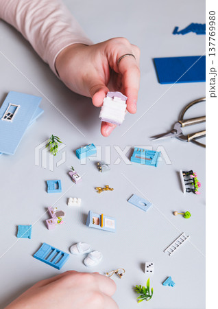 Miniature parts and furniture for a toy house in children's hands on a blue vertical view 137769980
