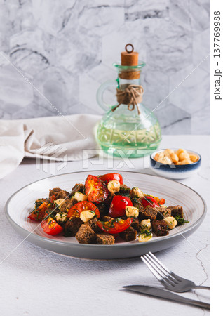 Salad of rye bread, cherry tomatoes and smoked cheese on a plate on the table vertical view Salad of rye bread, cherry tomatoes and smoked cheese on a plate on the table vertical view 137769988