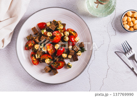 Salad of rye bread, cherry tomatoes and smoked cheese on a plate on the table top view Salad of rye bread, cherry tomatoes and smoked cheese on a plate on the table top view 137769990